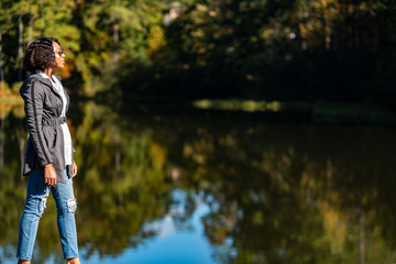 Beautiful young African-American Woman standing in front of lake in autumn