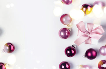 Christmas flat lay scene with pink and violet glass balls and gift box with pink bow, copy space on white