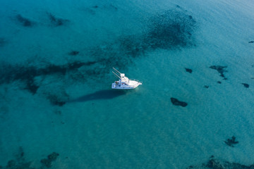 Aerial view of a little fishing boat on a beautiful and transparent sea. Sardinia, Italy..