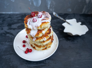 Hill of fresh cheesecakes pancakes on a ceramic plate, ripe grapes and light wooden background