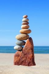 High pyramid of multicolored pebbles on a background of the summer sea.