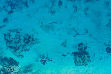 Aerial view of a beautiful turquoise and transparent sea that creates a natural pattern.
