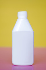 Plastic medicine bottle on the table, yellow background, white packaging