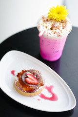 dessert time. A closed up of a lemon tart and an iced beverage of rose milk tea latte. selective focus on the strawberry top of lemon tart.