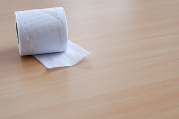 Tissue rolls used for wiping in a white bathroom are placed on a wooden background.