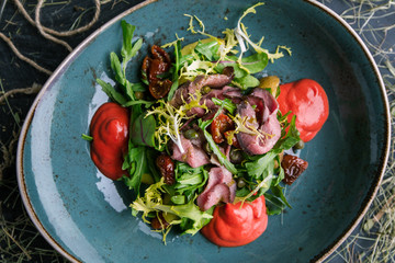 Meat salad with fresh herbs and dried tomatoes in a restaurant