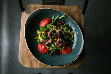 Meat salad with fresh herbs and dried tomatoes in a restaurant