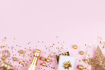 Christmas background with golden gift or present box, champagne and holiday decorations on pink...