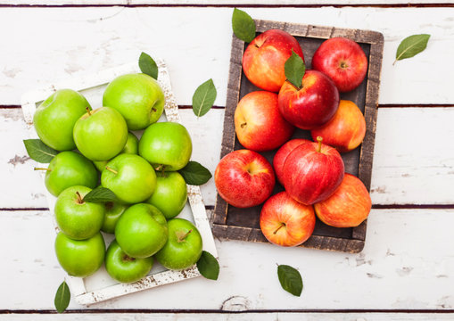 Healthy organic red and green apples in vintage box on wooden background.