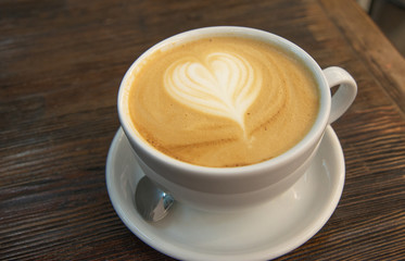 A cup of coffee with a pattern in the form of a heart on the milk foam. The big cup of cappuccino with latteart. Drawing on milk foam in the form of a heart.