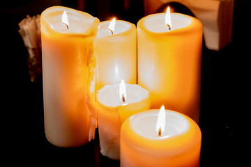Several burning candles on a dark background.