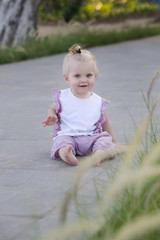 Adorable smiling baby girl sitting in the park pedestrian area