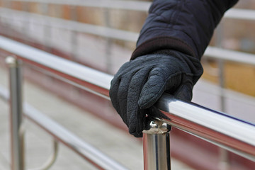 man's hand in glove holding hand rail while walking down stairs