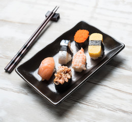 Sushi set with chopsticks on old wooden background