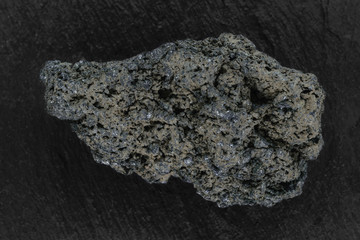 Black lava rock from Batur volcano placed on black stone background surface