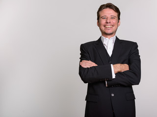 Happy Caucasian businessman with arms crossed looking at camera