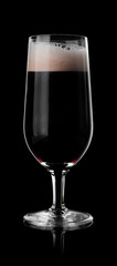 Glass of dark beer isolated on black background