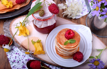 Stack of pancakes decorated with raspberry and mint on a white plate. Village style
