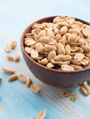 Roasted salted peanuts in wooden bowl on wooden table