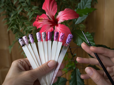 Nail design, the choice of pattern tips. Painted tips on the background of a red flower.
