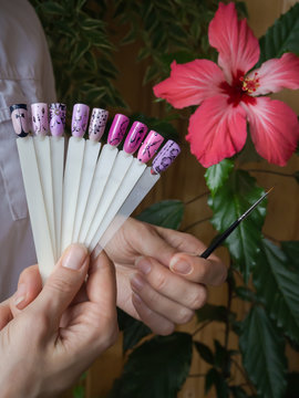 Nail design, the choice of pattern tips. Painted tips on the background of a red flower.
