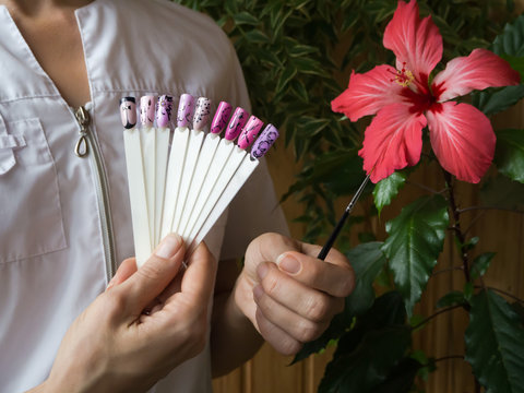 Nail design, the choice of pattern tips. Painted tips on the background of a red flower.

