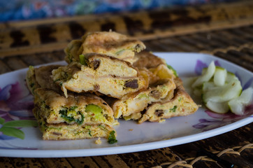 MARTABAK TELUR - stuffed pancake or pan-fried bread Indo-style on a plate, close-up.