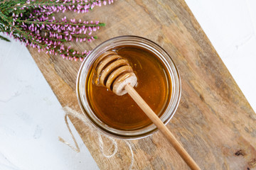 Obraz na płótnie Canvas Honey in jar with fresh heather on wooden background