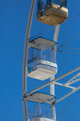 Giant ferris wheel with chairs, metallic structure, recreational element near the river