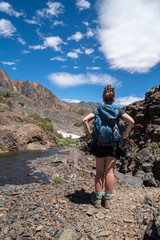 Adult female woman hiker stands on the 20 Lakes Basin trail in California, deciding and thinking about which way to go