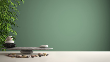 Empty interior design feng shui concept zen idea, white table or shelf with pebble balance and green bamboo, over green background copy space