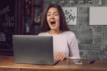 girl looks at laptop with horror, girl terrified