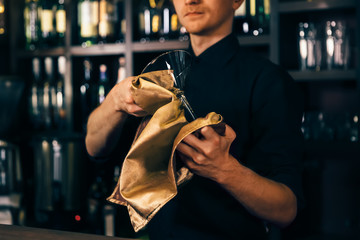 Barman is cleaning the glass with a cloth at bar counter background. The bartender cleaning the glass on the bar