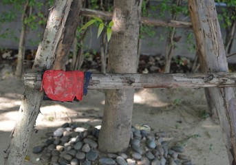 Red rags for cleaning are hung for drying on wood railings under the tree.