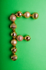 Letter F made of Christmas toys on green background. ABC