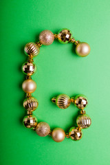 Letter G made of Christmas toys on green background. ABC