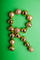 Letter R made of Christmas toys on green background. ABC