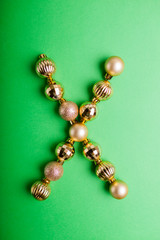 Letter X made of Christmas toys on green background. ABC