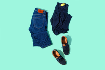 Flat lay set autumn male clothes jeans pullover shoes turquoise background top view