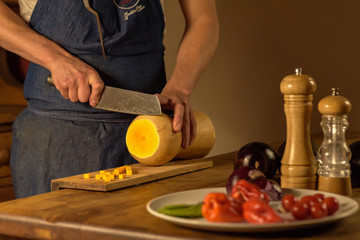 Chef cutting green onions on wooden board in dim light.