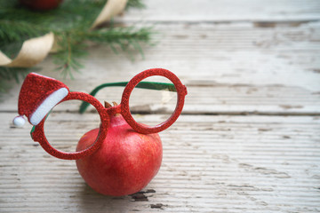 Vivid red Christmas pomegranates spectacles glasses with holiday decorative frame and fir tree...