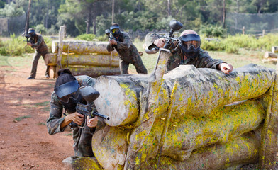 Portrait of team of adult people playing on paintball battlefield outdoor