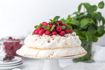 Pavlova cake with raspberries on a white cake stand