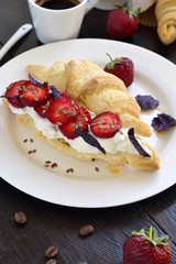 Croissant with cream cheese, strawberries and basil for breakfast