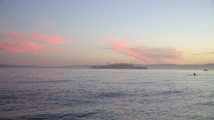Two racing shells sculling on San Francisco Bay at sunrise.  Alcatraz behind.  Gentle swell.