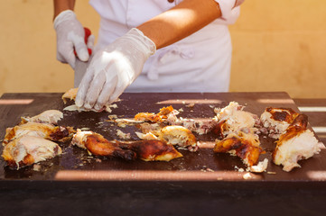 The chef's hand cuts the grilled chicken