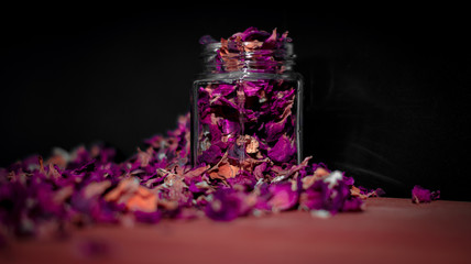 rote und lila Trockene Blumen Blüten in einem Glas mit schwarzen Hintergrund