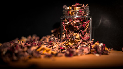 rote und gelbe Trockene Blumen Blüten in einem Glas mit schwarzen Hintergrund