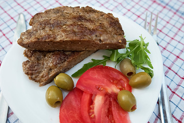Pleskavitsa. Dish of Balkan cuisine from minced meat with vegetables on white plate.