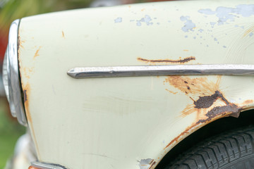 Close up of vintage old car with faded color and rust on the side